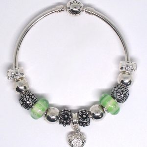 Green bangle bracelet with green, silver, heart clips, floral details, Murano glass beads, and European charms on an authentic Pandora bangle