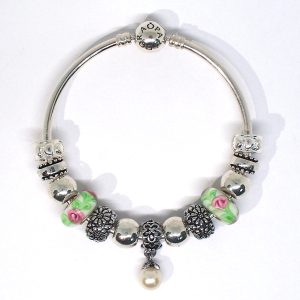 Pink floral bangle bracelet with pink, green, silver, red, heart clips, Murano glass, floral details, and European-style charms on an authentic Pandora bangle