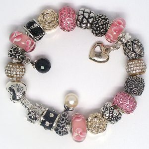 Pink charm bracelet with pink, black, gold, rose gold, silver, heart clip, Murano glass, pavé crystal, floral details, and European charms on an authentic Pandora bracelet