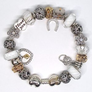 Graduation charm bracelet with S925 sterling silver charms, gold-plated accents, graduation cap, diploma, horseshoe, Murano glass, heart, daisy, and good luck charms on an authentic Pandora bracelet